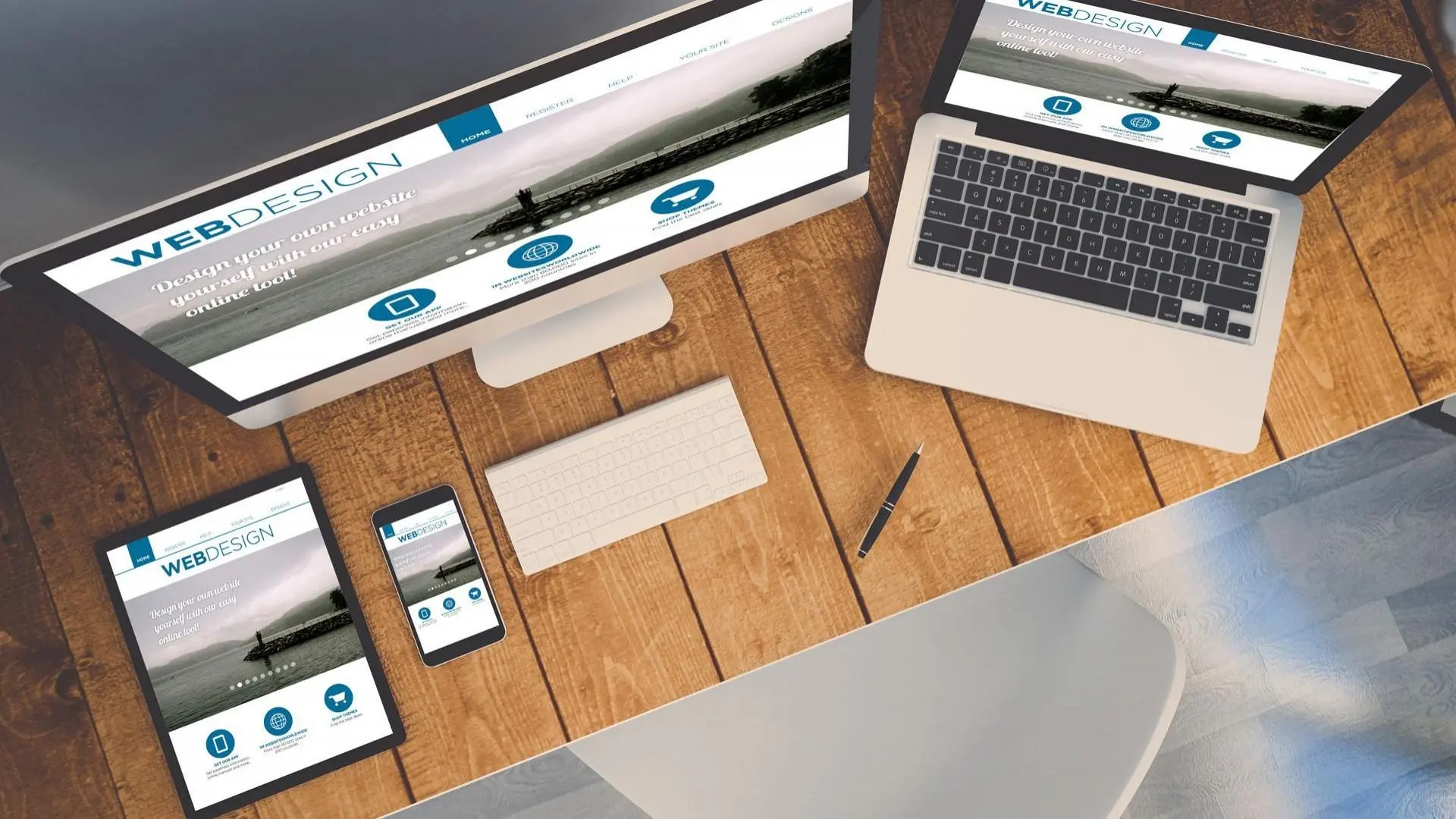 Ein Laptop, ein Mac-Rechner, ein Tablet und ein Handy liegen auf dem holzen Tisch