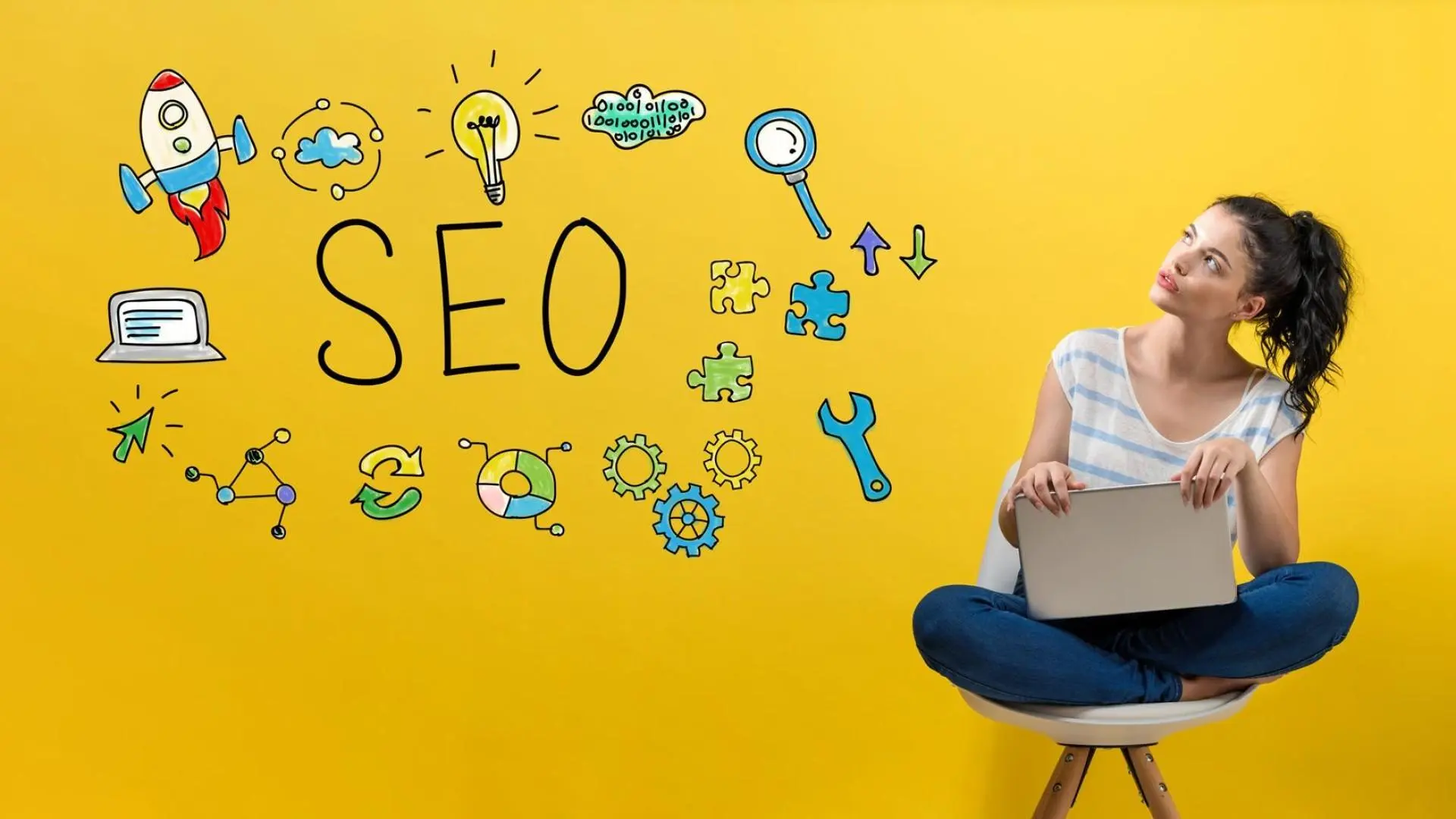 Eine junge Frau sitzt mit Ihrem Laptop auf einem Stuhl